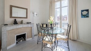 Ein Essbereich mit einem Glastisch, Metallstühlen, einem Kamin und einem Fenster mit Vorhängen.