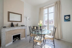 Ein Essbereich mit einem Glastisch, Metallstühlen, einem Kamin und einem Fenster mit Vorhängen.