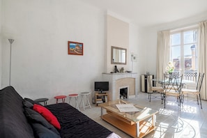 A living room with a sofa, a TV, a fireplace, and a dining area with chairs.