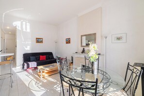Una sala moderna con una mesa de comedor de vidrio, sillas de metal negro, un sofá negro con cojines rojos y una chimenea.