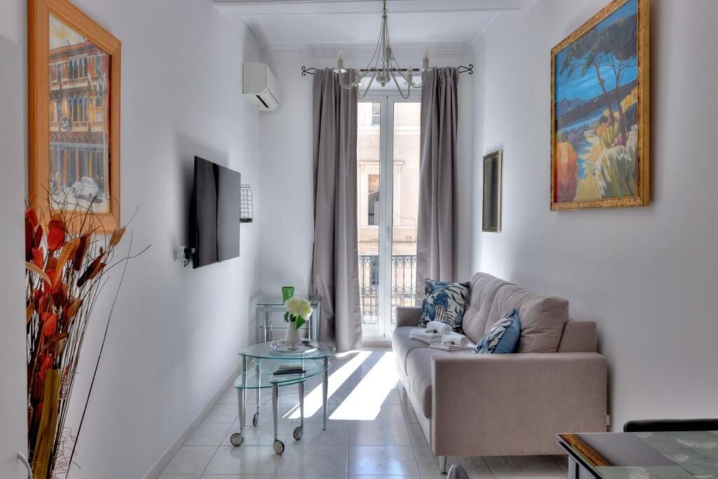 A modern living room with a sofa, a glass coffee table, and a painting on the wall.