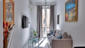 A modern living room with a sofa, a glass coffee table, and a painting on the wall.