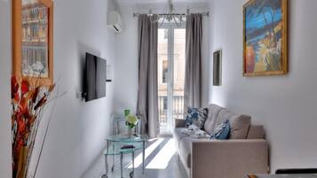 A modern living room with a sofa, a glass coffee table, and a painting on the wall.
