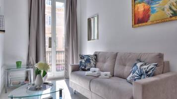 Un soggiorno moderno con un divano color beige, un tavolino in vetro e un quadro appeso al muro.