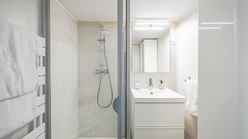 A modern bathroom with a glass-enclosed shower, a white sink, and a mirror above it.