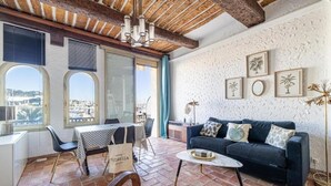 A cozy living area with a dark blue sofa, a coffee table, and a view of the city through large windows. - L'Honorat vue mer et port, à côté des plages (Cannes)