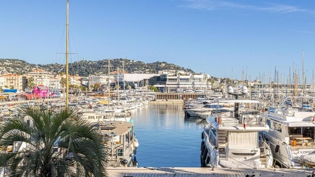 A marina with numerous boats docked, a clear sky, and buildings in the background. - L'Honorat vue mer et port, à côté des plages (Cannes)
