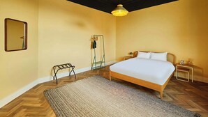 Ein Schlafzimmer mit einem Bett, einem Spiegel, einer Hängelampe, einem kleinen Tisch mit Lampe sowie einer Stehlampe.