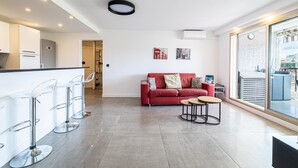 A modern kitchen with white cabinets, a red sofa, and a large window.