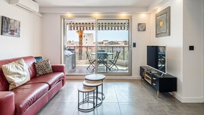 A modern living room with a red leather sofa, a small round table, and a TV stand.