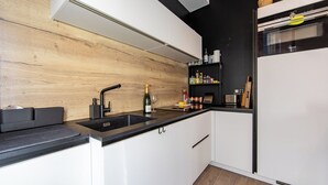 Una cocina moderna con protector contra salpicaduras de madera, armarios blancos y encimera negra.