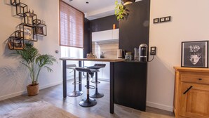 Una cocina moderna con una isla central, taburetes de bar, una planta en maceta y un mueble de madera.