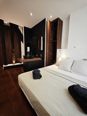 A modern bedroom with a large bed, a vanity with a mirror, and wooden accents. - The French Touch Duo, King Size Bed (Paris)