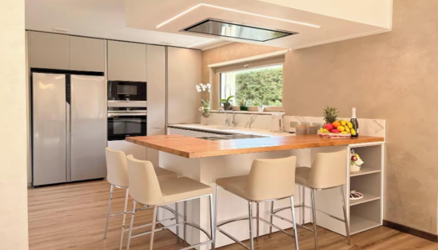 A modern kitchen with a central island, bar stools, and a built-in oven.