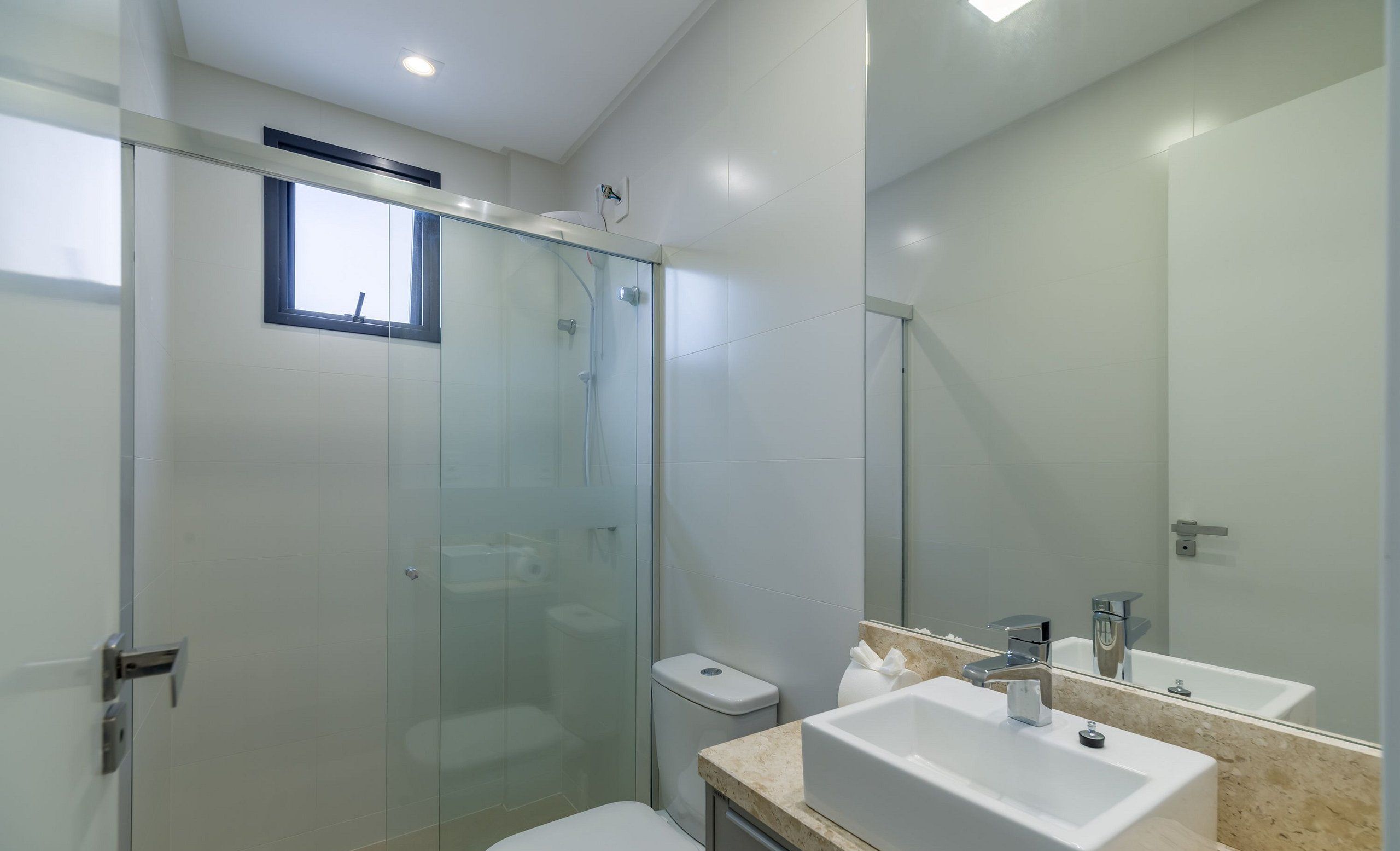 A modern bathroom with a glass shower enclosure, a toilet, and a sink with a mirror.