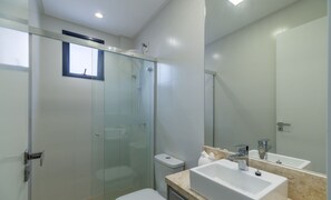 A modern bathroom with a glass shower enclosure, a toilet, and a sink with a mirror. - Apartment in Praia Brava, Itajai - Pvg0501 (Itajai)