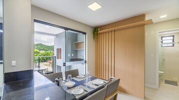 Cozinha moderna com área de refeições, porta de vidro deslizante para o exterior e vista para o verde.