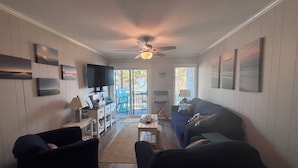 A living room with a ceiling fan, a TV, a sofa, and a coffee table.
