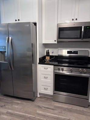 A kitchen with stainless steel appliances, including a refrigerator, microwave, and oven. - 'Just Chillaxin'-2-bedroom condo in lovely Ocean Isle Beach, NC-oceanview & pool (Ocean Isle Beach)