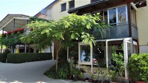 Un immeuble de deux étages doté d’un balcon, de plantes en pot et offrant une vue dégagée sur la rue.