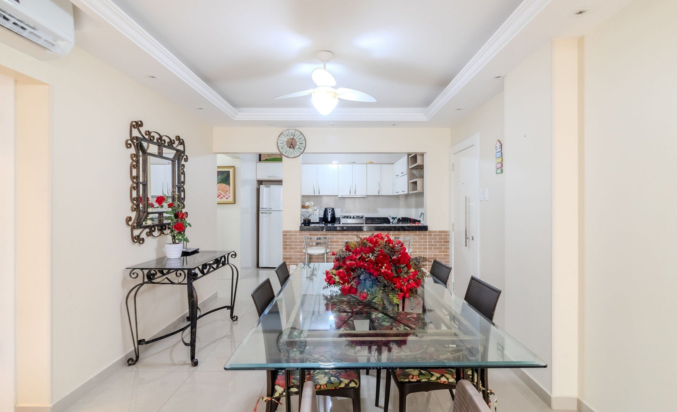 A dining area with a glass table, chairs, and a decorative mirror.