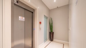 A hallway with a modern elevator, a potted plant, and a door with a light switch. - 3BR apt w/ Bbq, 500m From Beach Itapema Esm602 (Itapema)