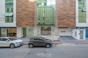Ein modernes Gebäude mit Glasfassade, einer Treppe zum Eingang und zwei parkenden Autos.