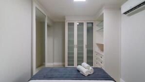 Un dormitorio con cama, armario de puertas de cristal y estantería empotrada.