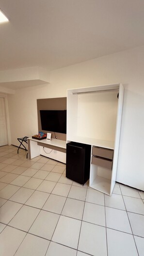 A room with a white desk, a black refrigerator, and a television on the wall. - Hotel Vistta Iracema (Fortaleza)