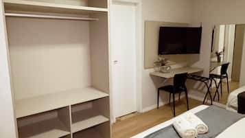 A bedroom with a bed, a desk, a chair, and a wardrobe.