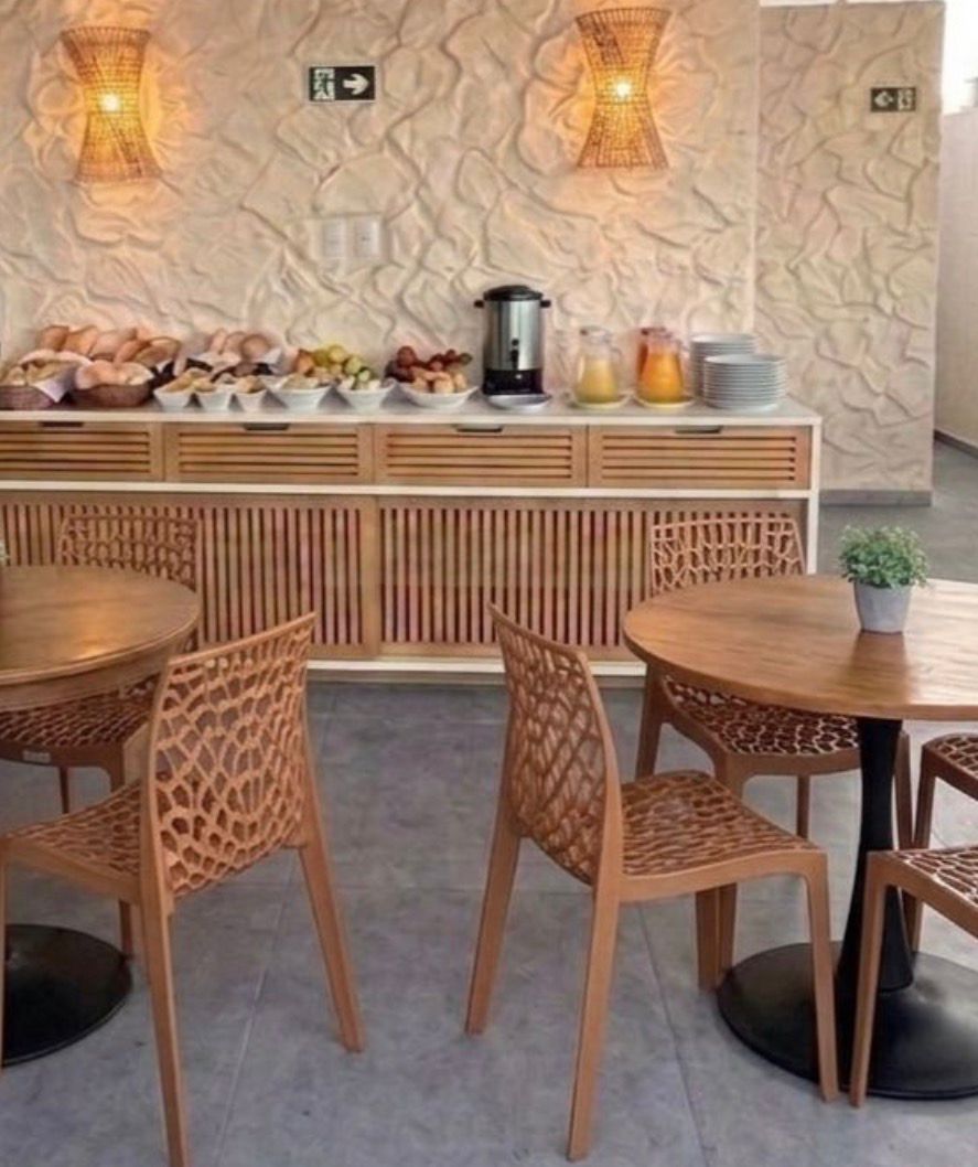 Un comedor con mesas y sillas redondas, un bufé con diversas opciones de comida y apliques decorativos en las paredes.