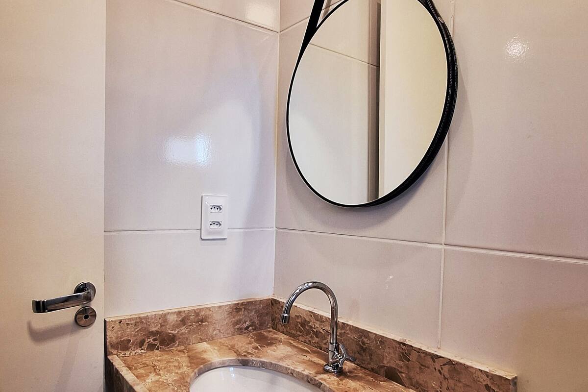 A bathroom with a marble sink, a mirror, a toilet, and a shower.