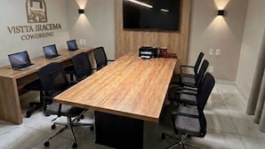 Une salle de conférence avec une longue table, des chaises, un téléviseur fixé au mur et un logo sur le mur.