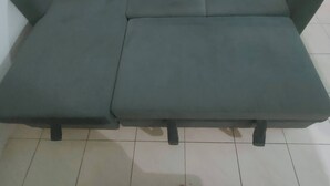 Ein grünes Sofa mit Chaiselongue in einem Raum mit Fliesenboden.