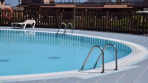 A swimming pool with a lifebuoy, a lounge chair, and a wooden fence.