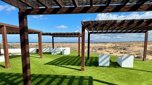 A pergola structure with artificial grass and white planters.