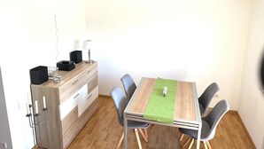 Et spiseområde med et træbord, stole, en loftventilator og et lille skab med en lampe.