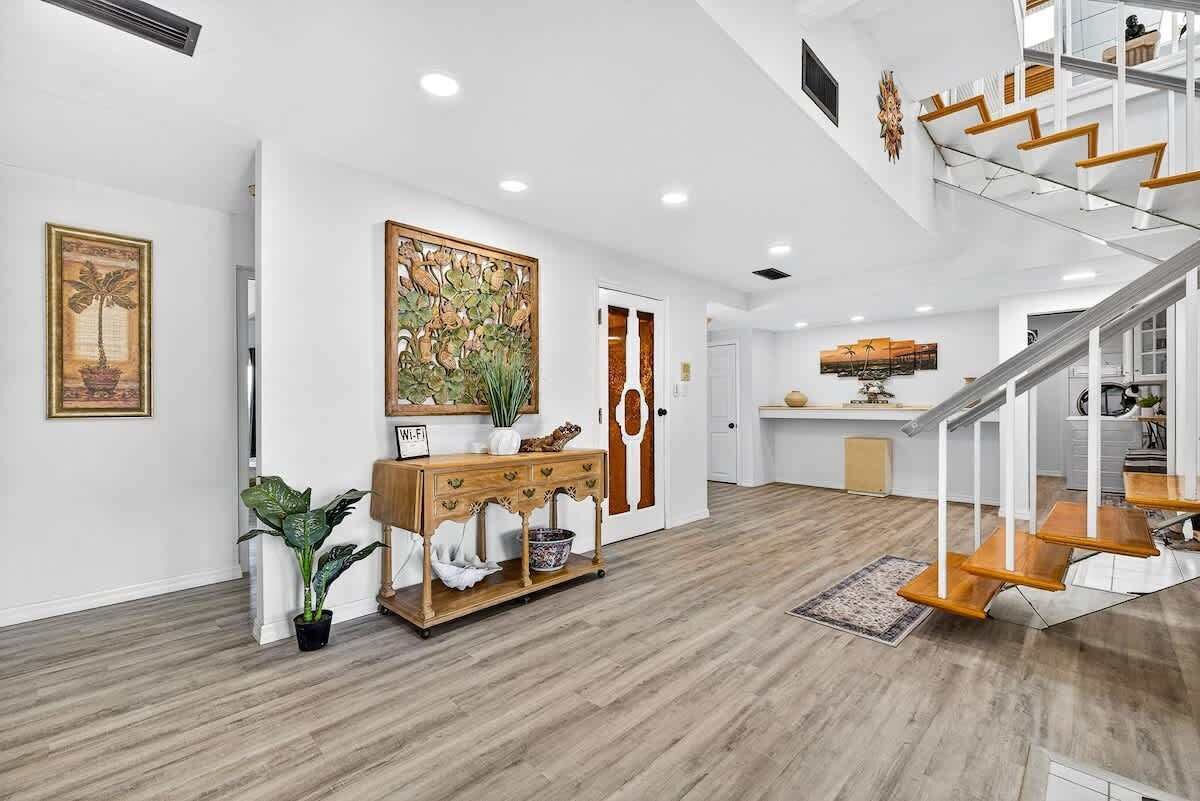 A modern interior with a wooden floor, a reception desk, a staircase, and a large painting on the wall.