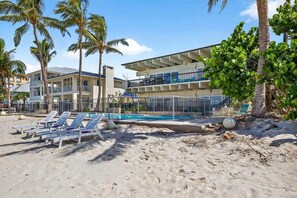 Un resort con piscina, sillas de descanso y palmeras.