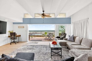 A modern living room with a ceiling fan, a sofa, a coffee table, and a view of the outdoors.
