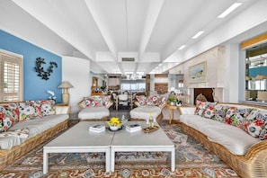 A spacious living area with wicker sofas, a coffee table, and a patterned rug.
