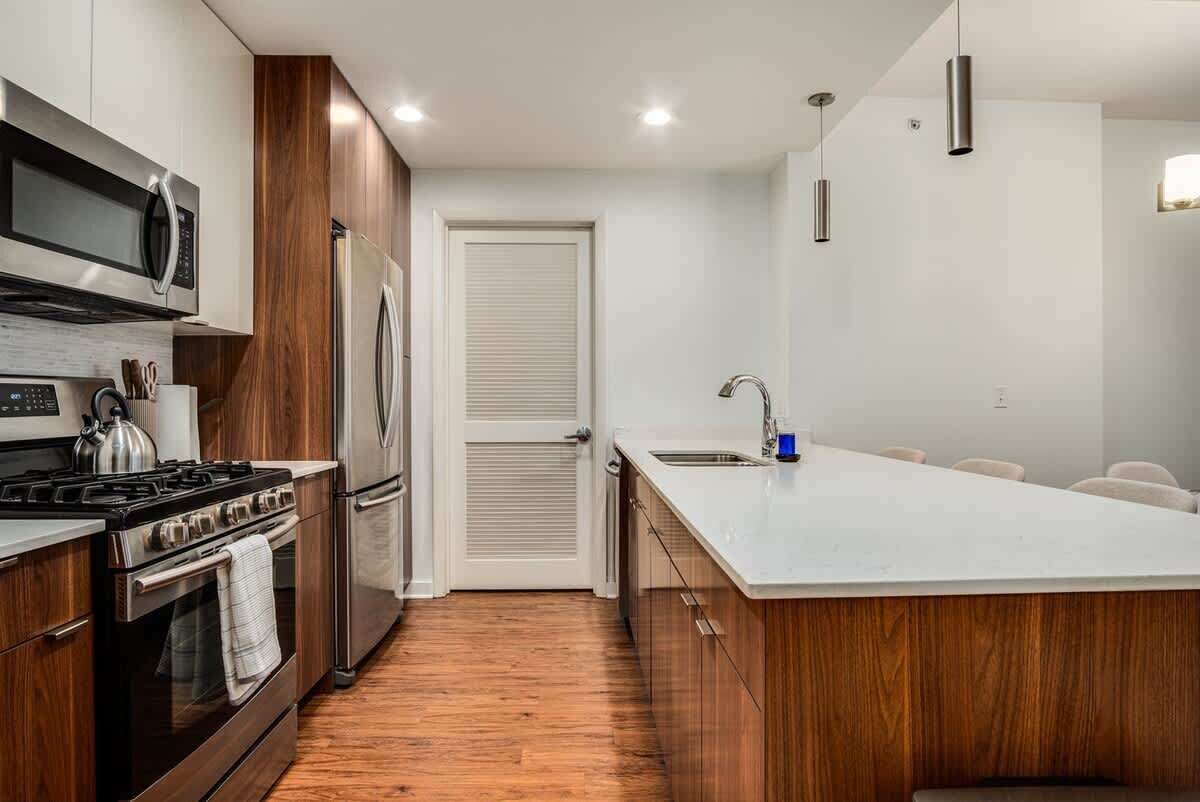 Una cocina moderna con una isla central, electrodomésticos de acero inoxidable y armarios de madera.