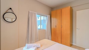 A bedroom with a bed, a wardrobe, a window with curtains, and a mirror on the wall. - Apartamento 70m del mar Cerca de Todo en BC Pol406 (Balneário Camboriú)