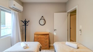 A hotel room with two beds, a wooden dresser, a coat rack, a mirror, and an air conditioning unit. - Apartamento 70m del mar Cerca de Todo en BC Pol406 (Balneário Camboriú)