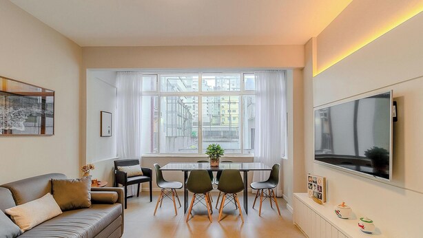 A modern living room with a sofa, dining table, chairs, a TV, and a large window with curtains. - Apartamento 70m del mar Cerca de Todo en BC Pol406 (Balneário Camboriú)
