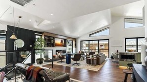 Un salón amplio con chimenea, asientos cómodos y un gran ventanal que proporciona luz natural.