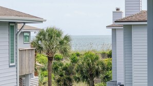 A coastal view with a house and a palm tree in the foreground, overlooking the sea.