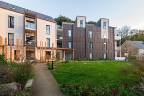 Un immeuble résidentiel moderne doté de nombreux balcons, d’un chemin pavé et d’une pelouse bien entretenue.