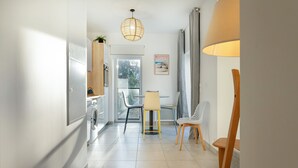 A modern kitchen with a washing machine, a dining area with a table and chairs, and a large window. - Apartment 'Regard Marin - 4 People' with Balcony (Le Palais)