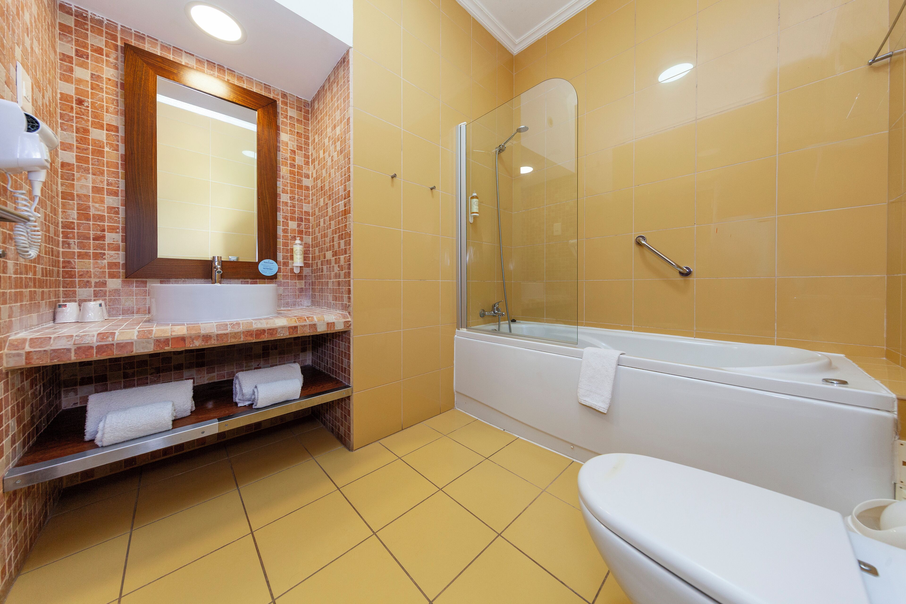 A bathroom with a glass-enclosed shower, a white bathtub, and a sink with a mirror above it.